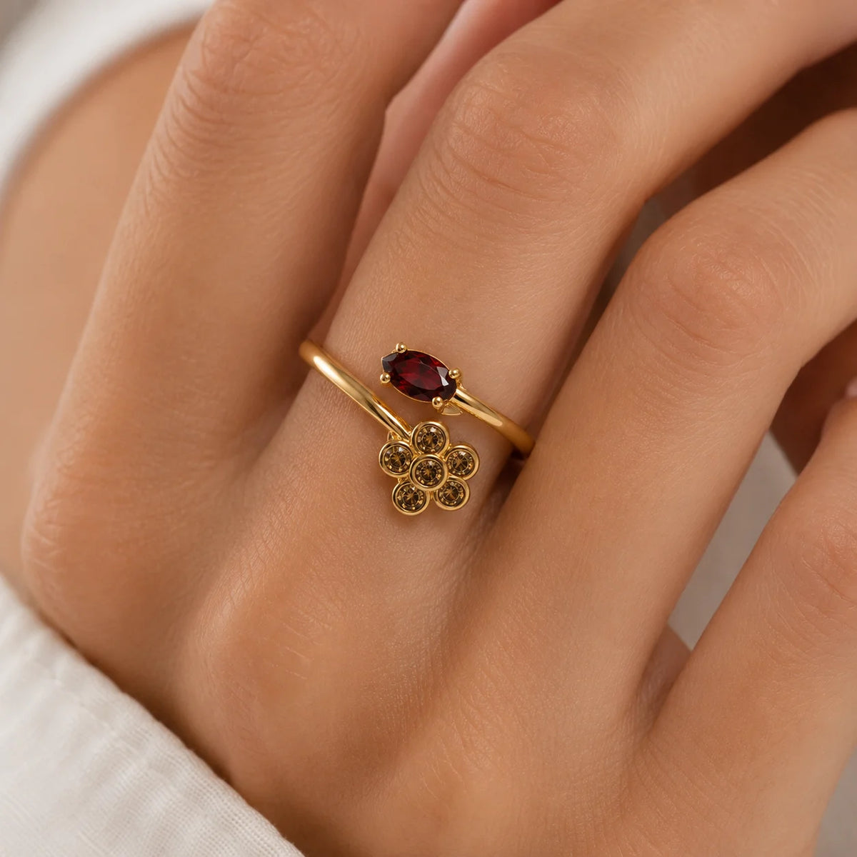 Primer plano de la mano con el anillo de flor y piedra roja