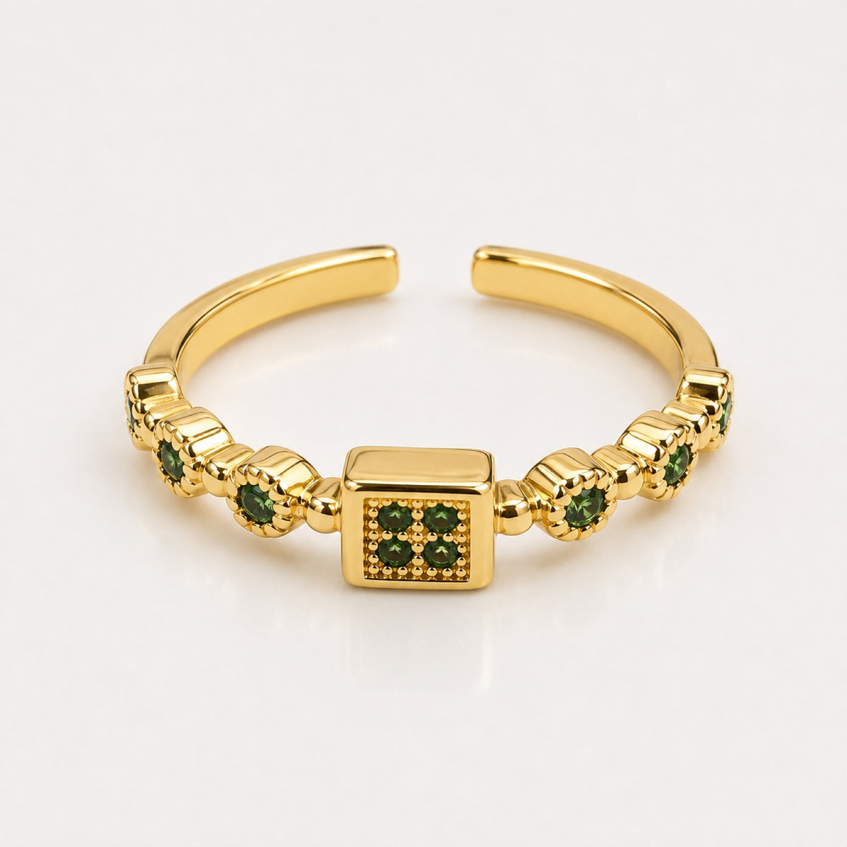 Anillo dorado ajustable con cuadro central y piedras verdes a los lados