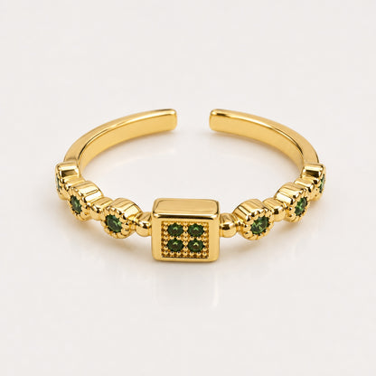 Anillo dorado ajustable con cuadro central y piedras verdes a los lados
