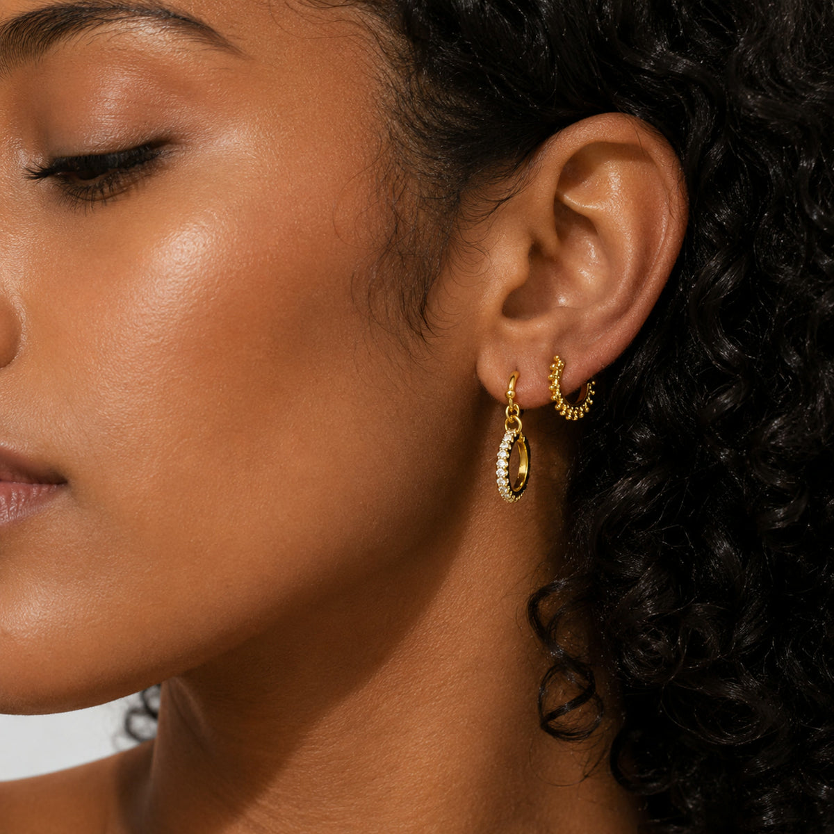 Aretes de aro con perla y colgante puestos en la oreja
