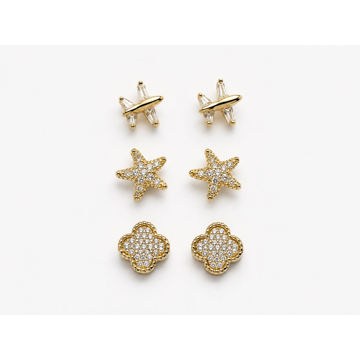 Set de tres pares de aretes dorados en pavé con forma de avión, estrella y trébol
