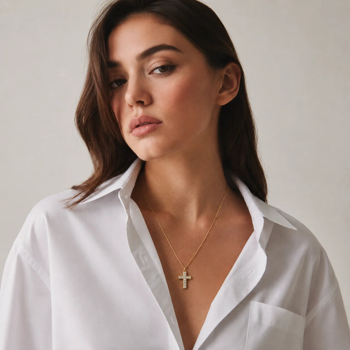Mujer con camisa blanca y el collar de cruz dorada puesto