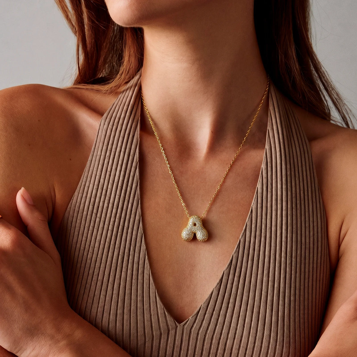 Collar de inicial bubble en oro puesto, la cadena cae debajo de la clavícula
