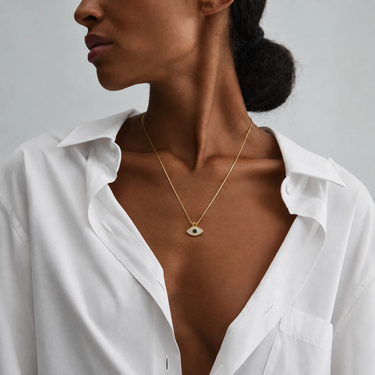 Mujer con camisa blanca abierta y el collar de ojo turco puesto