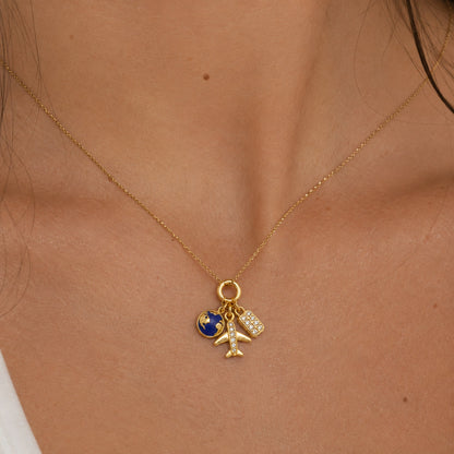 Charm de viajes colgado de una cadena, puesto al cuello, en otro plano