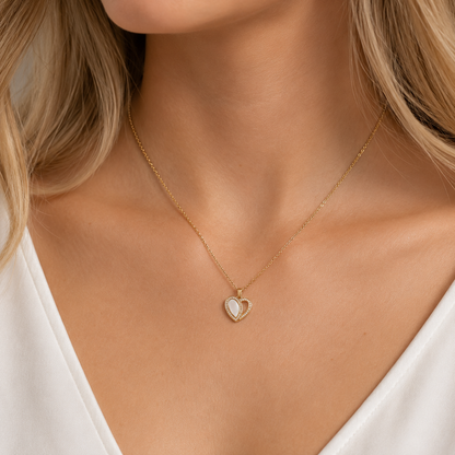 Mujer con top blanco y el dije de corazón de nácar puesto al cuello