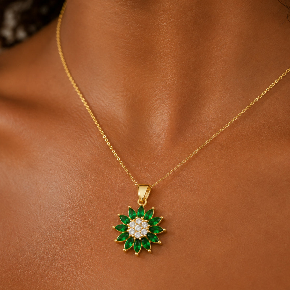 Dije de flor con piedras verdes puesto al cuello, en otro plano