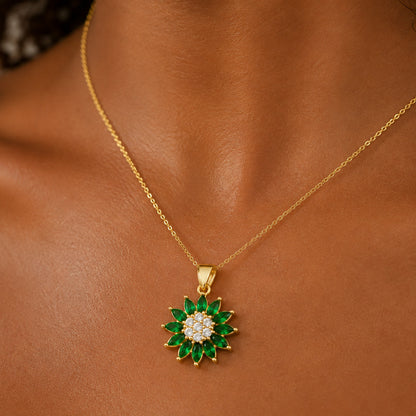 Dije de flor con piedras verdes puesto al cuello, en otro plano