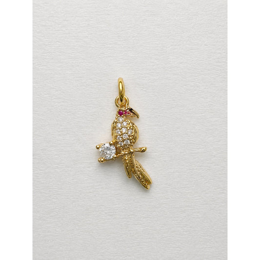 Dije dorado de loro posado en una rama con pavé de circonias