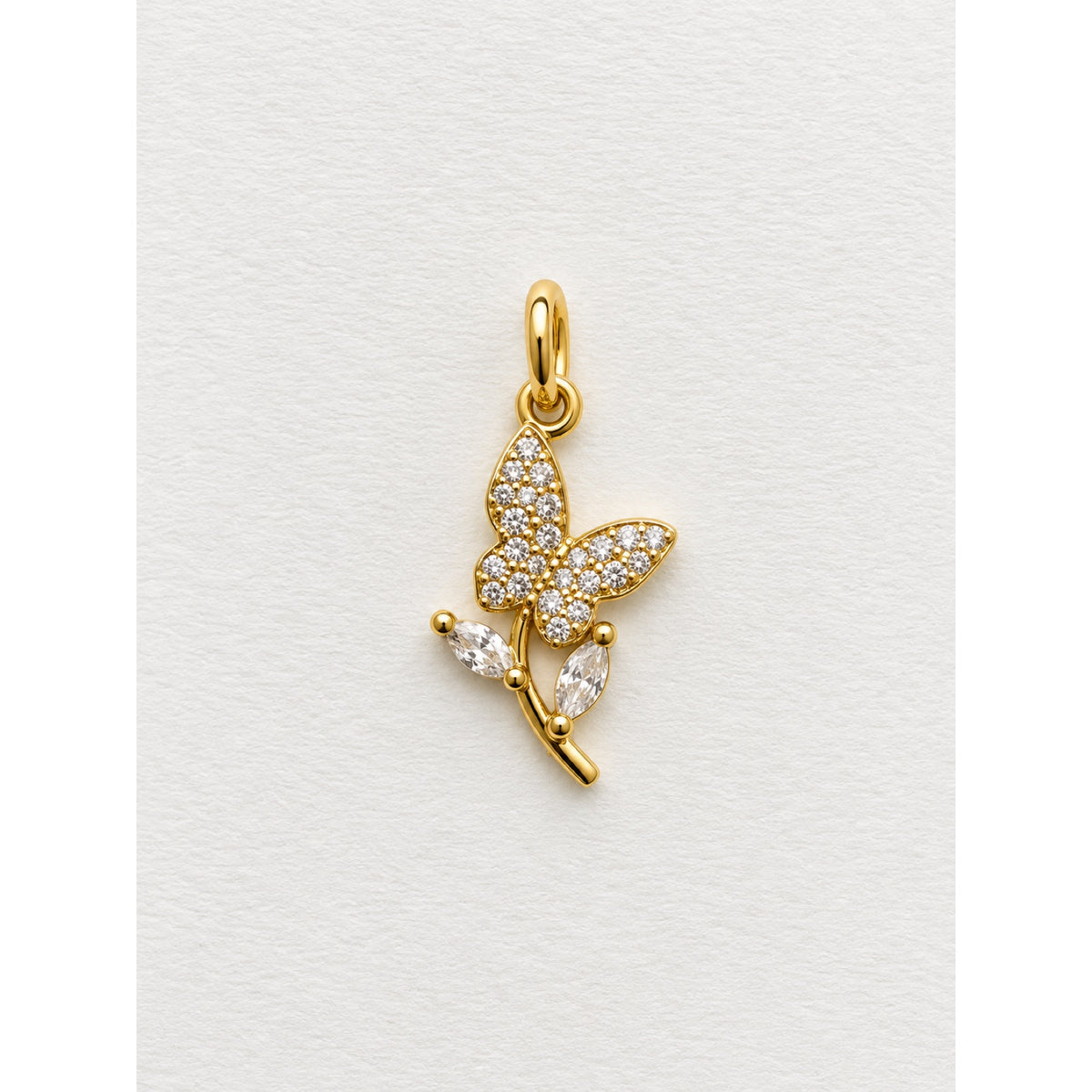 Dije dorado de mariposa en pavé de circonias posada sobre una rama