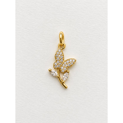 Dije dorado de mariposa en pavé de circonias posada sobre una rama