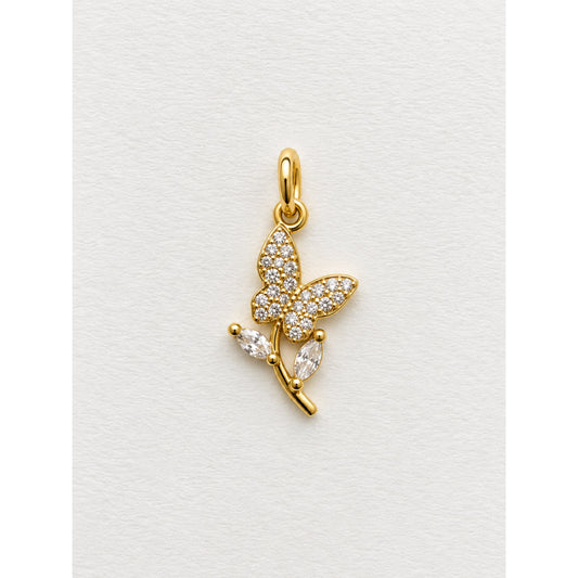 Dije dorado de mariposa en pavé de circonias posada sobre una rama