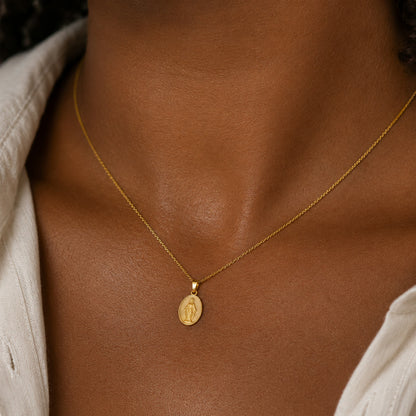 Dije de la medalla de la Virgen Milagrosa puesto al cuello, en otro plano