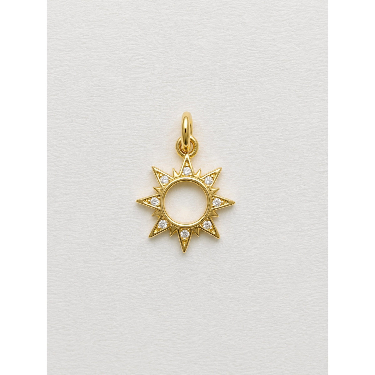 Dije dorado de sol con rayos y contorno en pavé de circonias