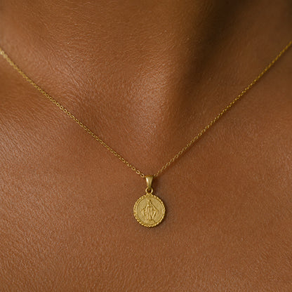 Dije de la medalla de la Virgen María puesto al cuello, en otro plano